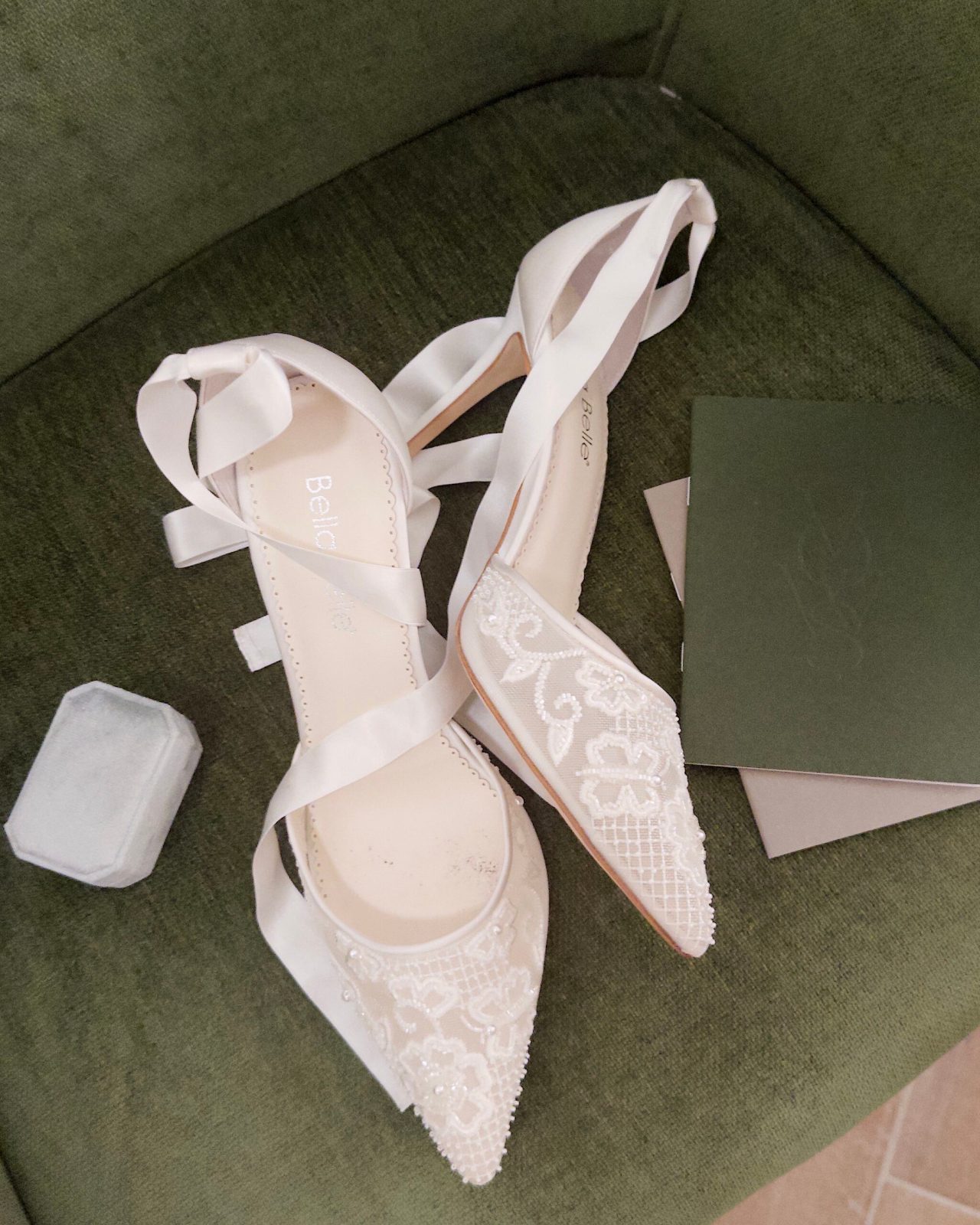 Pair of white bridal heels on a green velvet chair