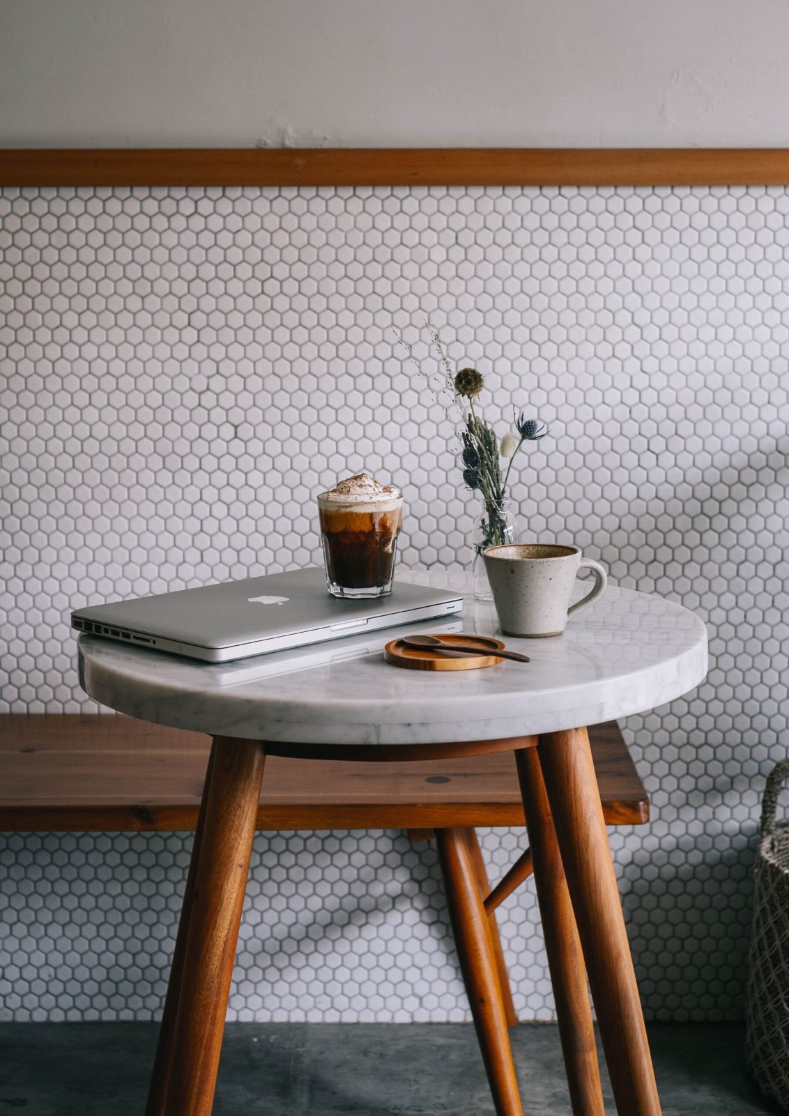 Small cafe table and stool against a white brick wall