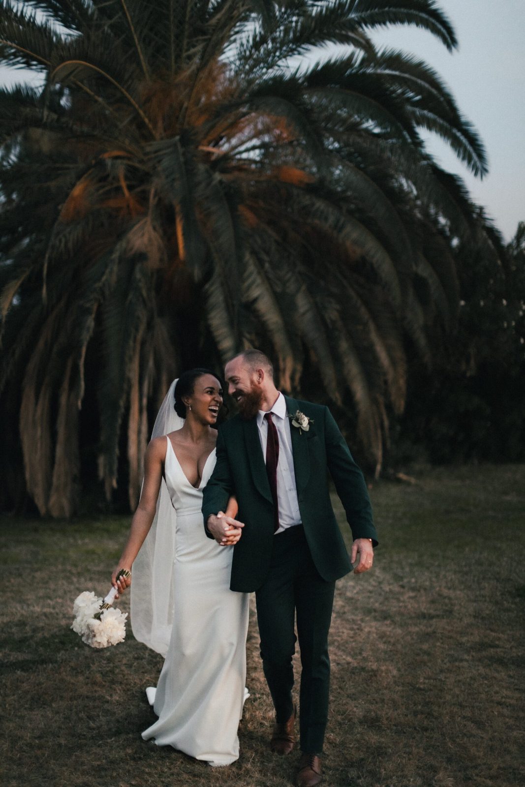 Bride and groom walking under palm trees