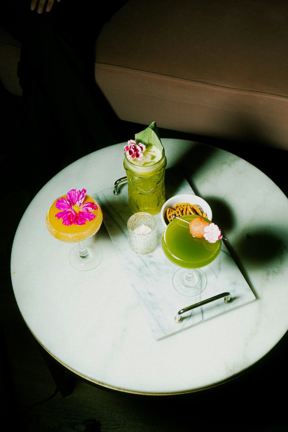 green and yellow cocktails on a tray with flower garnishes