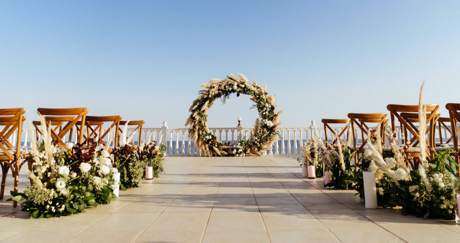 Oceanfront ceremony aisle leading to a round floral arch