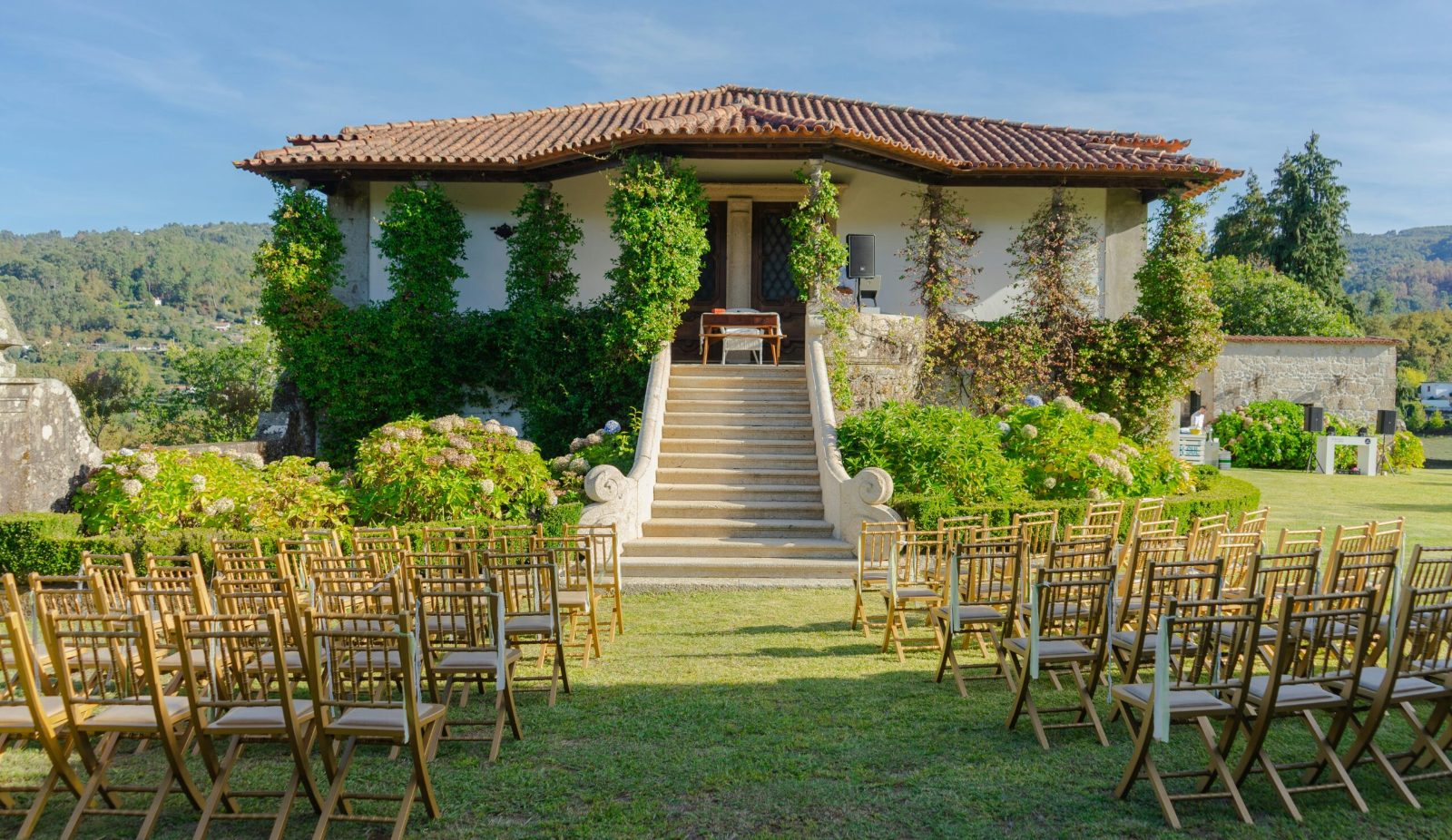 Outdoor wedding ceremony seating in front of an ivy-covered villa