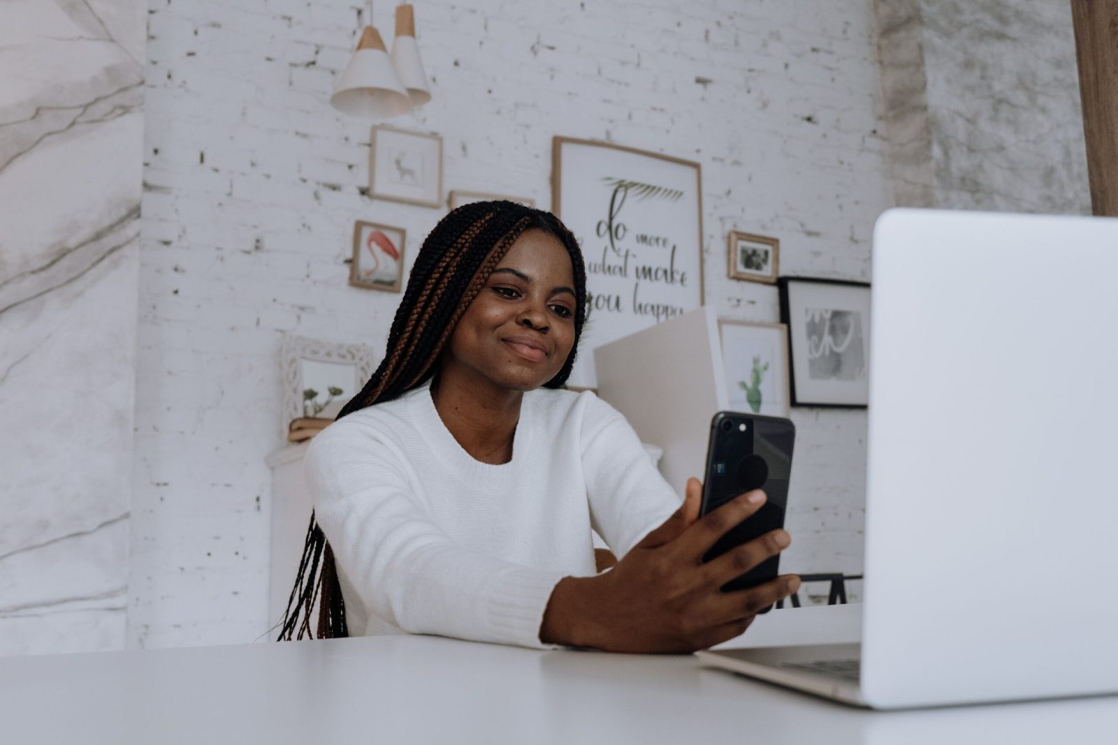 Smiling woman holding up her phone at a desk